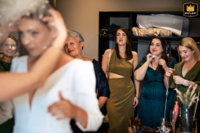 A beautiful bride, surrounded by friends, is putting on the finishing touches to her attire at Domaine Etxezahar in Bardos, France. The palpable emotion in the air is captured in this stunning wedding day image.